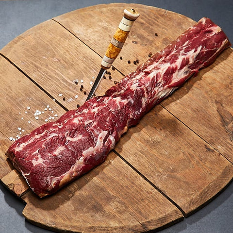 Ytterfilé från svensk björn på träplatta med kniv och salt
