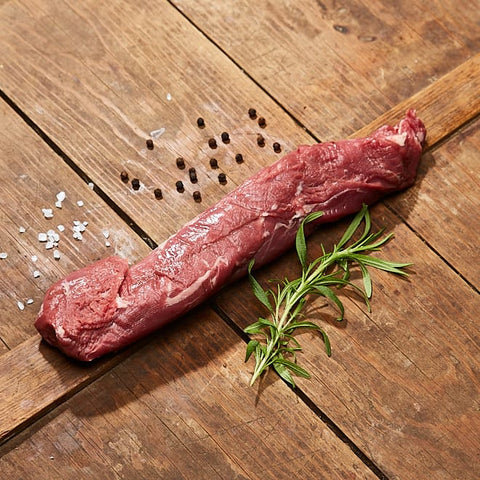 Svensk vildsvin innerfilé med kvist och salt och peppar på träbord